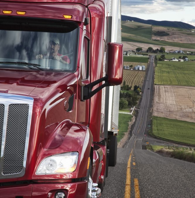 Close up view of the cab and driver of a commercial truck on the highway.